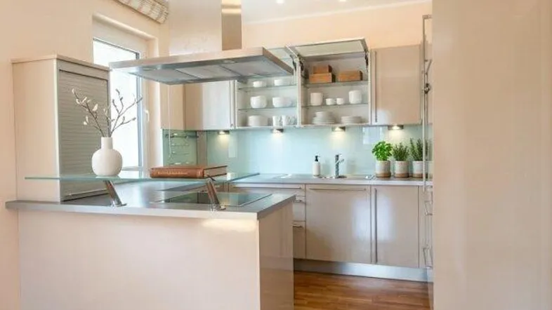 Moderne Küche mit heller Einrichtung, Kücheninsel und Holzboden, ausgestattet mit Dunstabzugshaube.