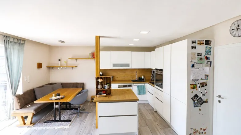 Moderne offene Küche mit Essbereich und Holzelementen, integriert in einen hellen Wohnraum.