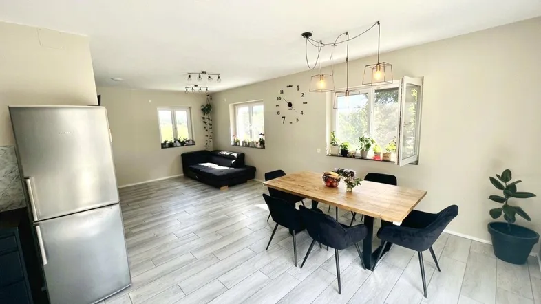 Helles offenes Wohnzimmer mit Essbereich, Fliesenboden und einem modernen Kühlschrank.