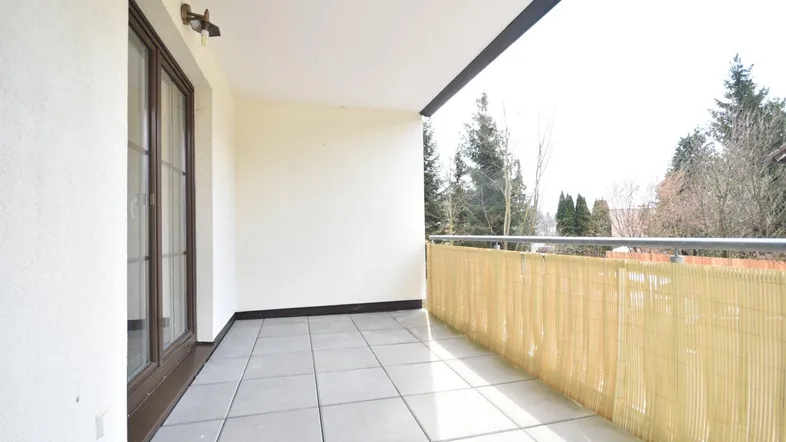 Heller Balkon mit Fliesenboden, Bambussichtschutz und Blick ins Grüne.