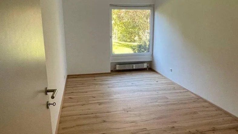 Helles Zimmer mit neuem Laminatboden und Blick ins Grüne, ideal als Schlaf- oder Arbeitszimmer.