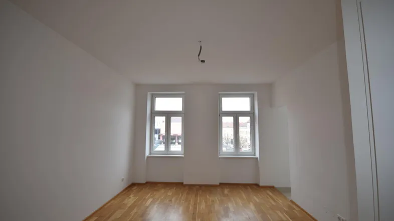 Heller, leerer Raum mit frisch gestrichenen weißen Wänden und schönem Parkettboden.