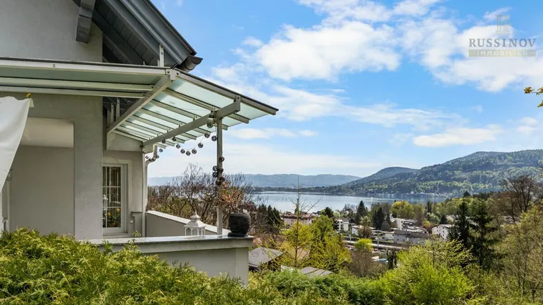 Blick auf den See und die umliegende Landschaft von der überdachten Terrasse des Hauses.