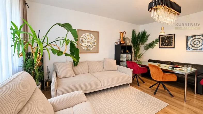 Helles Wohn- und Esszimmer mit bequemen Sofas, Esstisch und dekorativen Pflanzen.