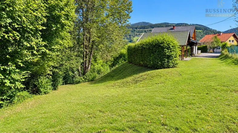 Weitläufige Grünfläche mit gepflegtem Rasen und Blick auf die umliegende Natur und Berge.