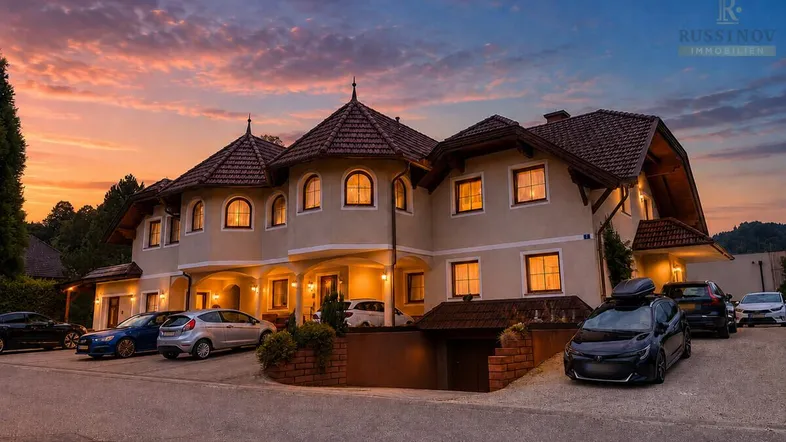 Ansprechendes Mehrfamilienhaus mit traditioneller Architektur und Parkplätzen bei Sonnenuntergang.