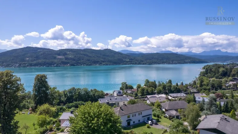 Panoramablick auf den Wörthersee mit umliegenden Häusern und grüner Landschaft.
