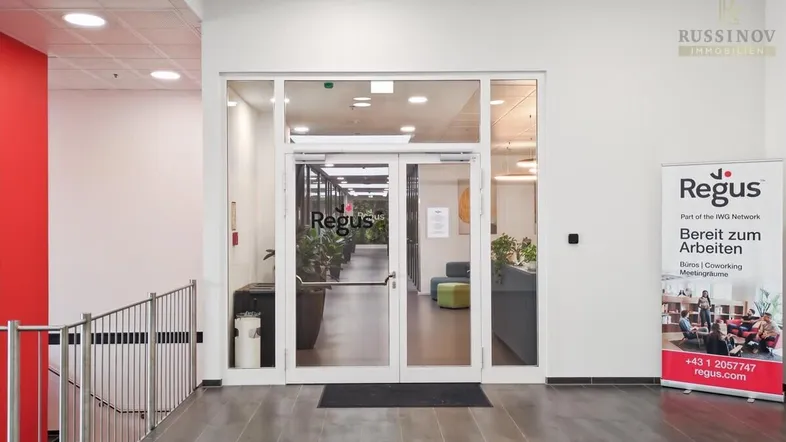 Heller Eingangsbereich mit Glastüren und einem Regus-Werbebanner, der zu modernen Büroräumen führt.