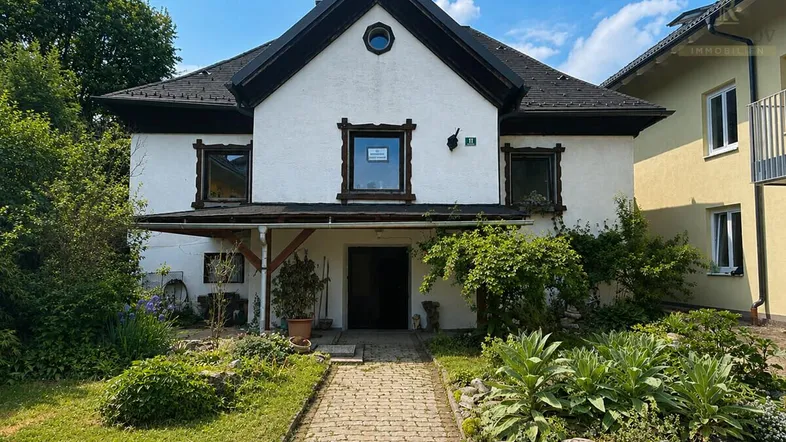 Vorderansicht eines charmanten Hauses mit gepflegtem Vorgarten und traditionellen Holzelementen.
