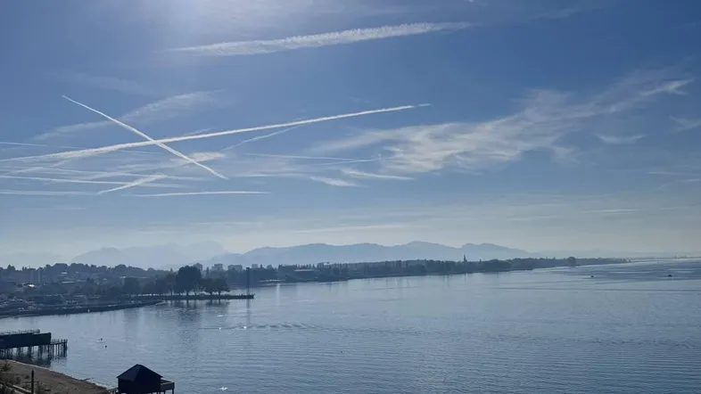 Panoramablick auf den See, die Stadt und die umliegenden Berge an einem sonnigen Tag.