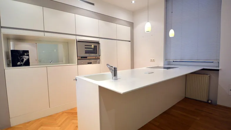 Moderne Küche mit weißer Kücheninsel, integrierten Geräten und Fischgrätparkettboden.