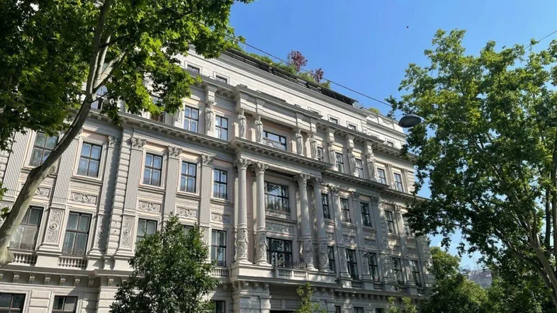 Prächtige Fassade eines historischen Gebäudes mit aufwendigen Verzierungen und hohen Fenstern.