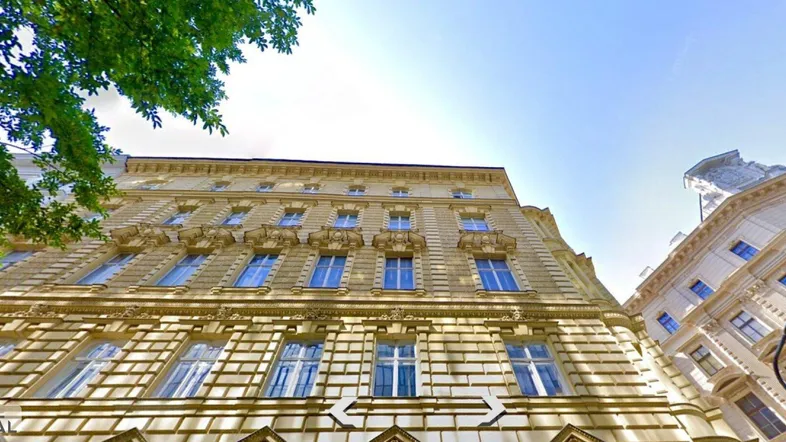 Historisches Gebäude mit reich verzierter Fassade und blauen Fenstern unter klarem Himmel.