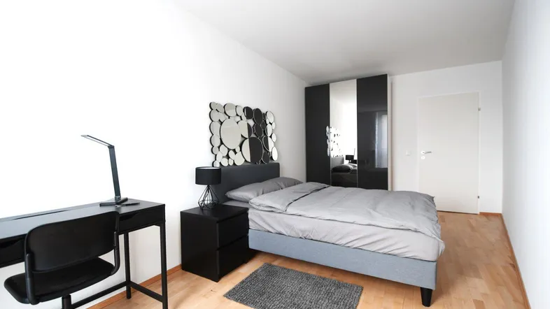 Modernes Schlafzimmer mit Schreibtisch, Kleiderschrank und hellem Parkettboden.
