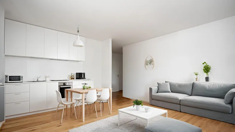 Heller, offener Wohn-Essbereich mit moderner weißer Küche und Parkettboden, ideal für geselliges Beisammensein.