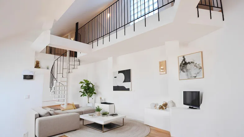 Heller, offener Wohnbereich mit hoher Decke, Wendeltreppe zur Galerie und moderner Einrichtung.