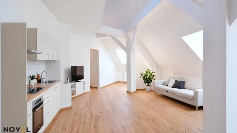 Offener Wohnbereich mit integrierter Küchenzeile, Dachschrägen und Holzboden, hell durch Dachfenster.