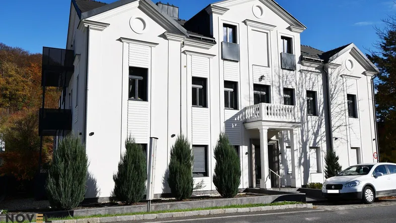 Elegantes weißes Gebäude mit klassischer Architektur und gepflegter Außenanlage.