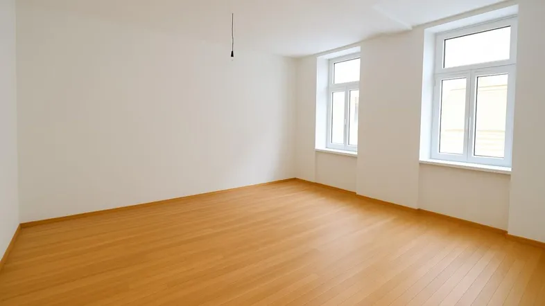 Helles, leeres Zimmer mit Parkettboden und zwei großen Fenstern, bereit zur individuellen Gestaltung.