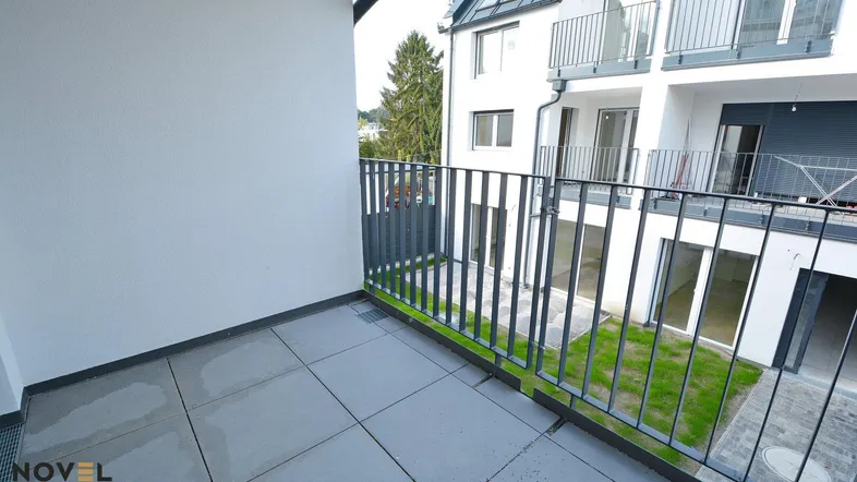 Geräumiger Balkon mit Fliesenboden und Blick auf den Innenhof des modernen Gebäudes.
