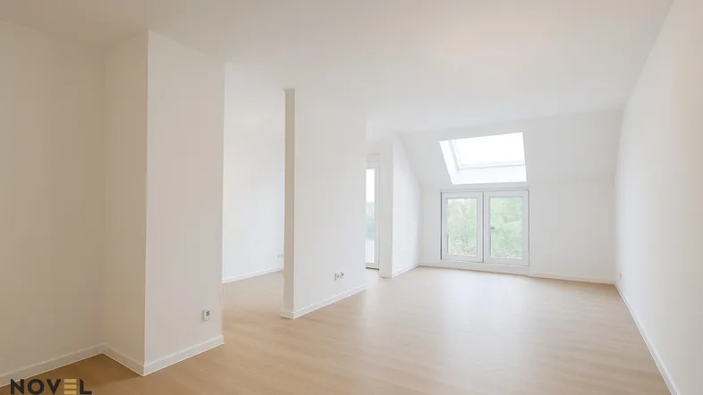Helles, unmöbliertes Wohnzimmer mit Dachschrägen, Dachfenster und hellem Laminatboden.