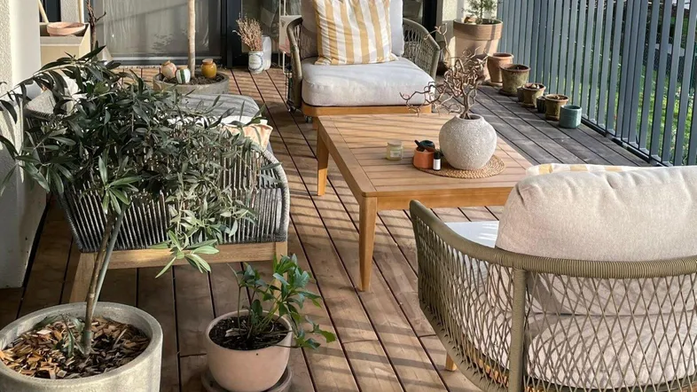 Geräumiger Balkon mit Holzboden, bequemen Sitzmöbeln und Pflanzen, ideal zum Entspannen im Freien.