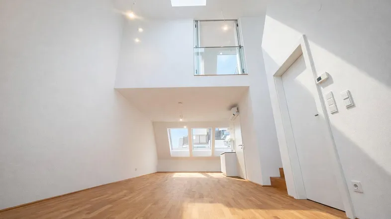 Helles, offenes Wohnzimmer mit hohen Decken, Holzfußboden und Dachfenstern, inklusive Galeriebereich.