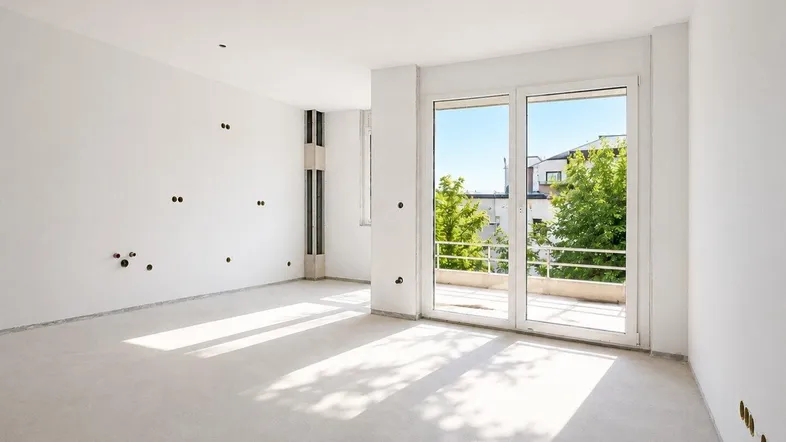 Heller, unmöblierter Raum mit großen Fenstern und Zugang zu einem Balkon, ideal für ein Wohnzimmer.