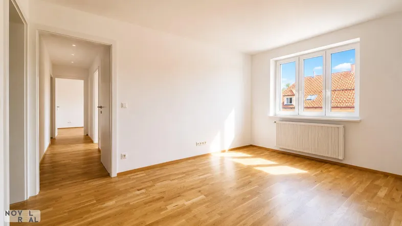 Geräumiger, heller Wohnbereich mit Holzboden und Blick auf die Dächer der Nachbarschaft.