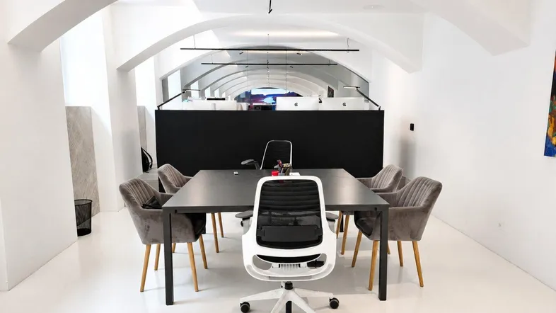 Moderner Bürobereich mit gewölbten Decken, einem großen Konferenztisch und ergonomischen Stühlen in einem hellen Raum.