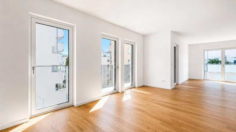 Helles Wohnzimmer mit Eichenparkettboden und Zugang zu mehreren französischen Balkonen.