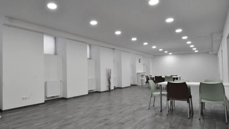 Großer, heller Gemeinschaftsraum mit modernen Fliesen in Holzoptik und eingelassener Deckenbeleuchtung.