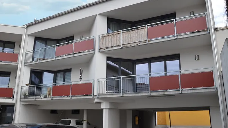 Moderne Wohnanlage mit mehreren Balkonen und überdachten Parkplätzen im Erdgeschoss.
