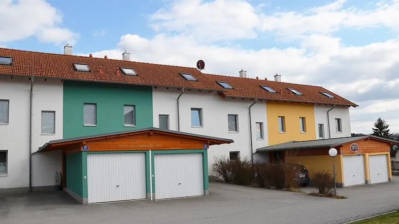 Reihenhäuser mit farbiger Fassadengestaltung, Satteldach und integrierten Carports.