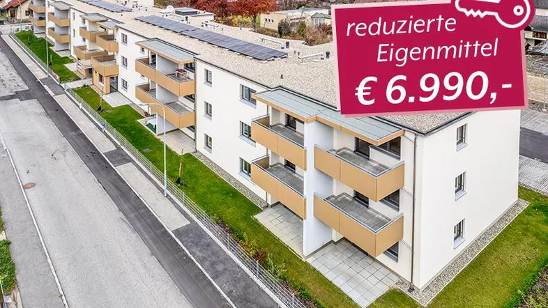 Mehrere moderne Wohngebäude mit Balkonen und Solaranlagen auf den Dächern, umgeben von Grünflächen.