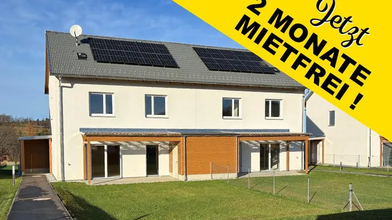 Modernes Reihenhaus mit Photovoltaikanlage auf dem Dach und grünem Gartenbereich, beworben mit zwei mietfreien Monaten.