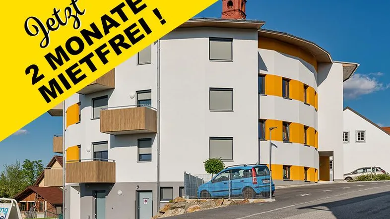Modernes Mehrfamilienhaus mit runder Architektur und gelben Akzenten, umgeben von Grünflächen.