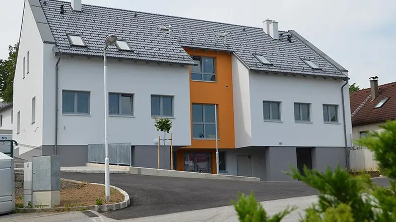 Ansicht eines modernen Mehrfamilienhauses mit orangefarbenen Akzenten und Dachfenstern.