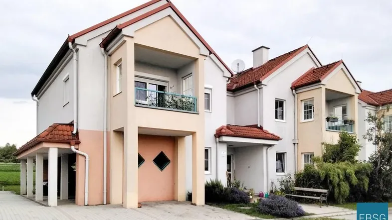 Mehrfamilienhaus mit mehreren Wohneinheiten, Balkonen und Satteldach in ländlicher Umgebung.