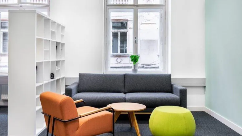 Gemütlicher Loungebereich in einem modernen Büro mit Sofa, Sessel, Couchtisch und Bücherregal.