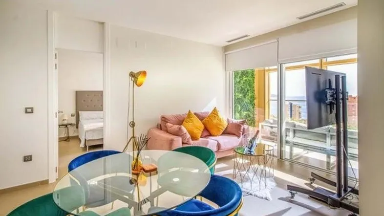 Helles Wohn- und Esszimmer mit modernem Mobiliar, Meerblick und Zugang zum Balkon.