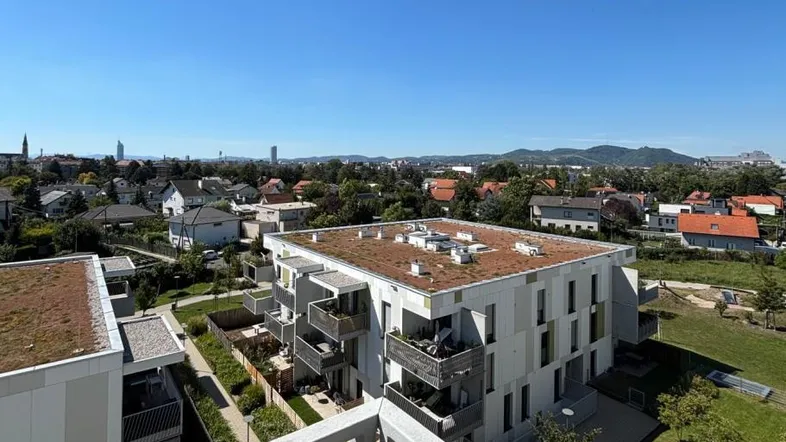 Panoramablick von einem Balkon über eine moderne Wohnsiedlung mit Gründächern und Stadtkulisse.