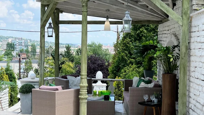 Überdachte Terrasse mit bequemen Outdoor-Möbeln und weitem Blick über die Stadt.