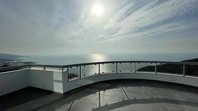 Große Terrasse mit Glasgeländer und weitem Blick auf das Meer und die Küste.