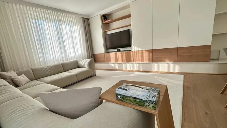 Helles Wohnzimmer mit großem Ecksofa, Holzboden und integriertem Medienmöbel.