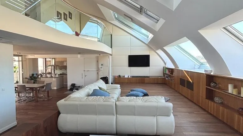 Großzügiger, lichtdurchfluteter Wohnbereich mit hohen Decken, Dachfenstern und elegantem Holzboden.