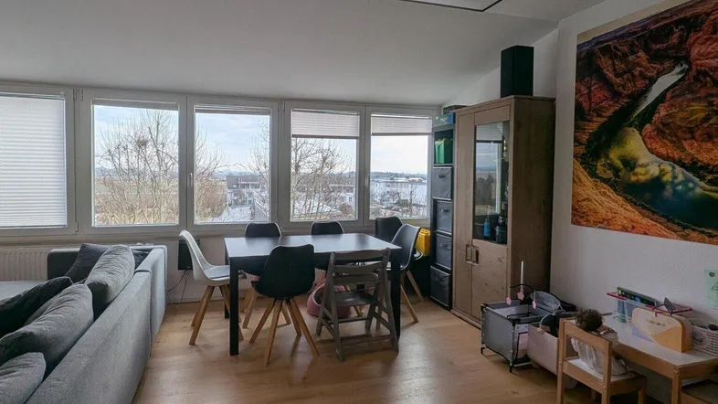 Helles Wohn- und Esszimmer mit Holzboden, großem Esstisch und Blick ins Grüne.