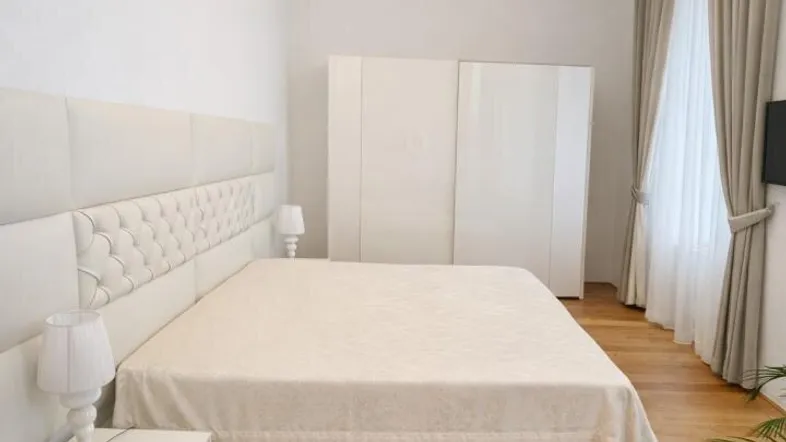 Helles Schlafzimmer mit großem Bett, weißem Kleiderschrank und eleganten Deckenleuchten.