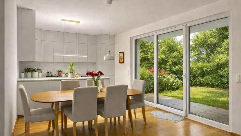 Moderne Küche mit Essbereich, hellen Fronten und direktem Zugang zum grünen Garten.