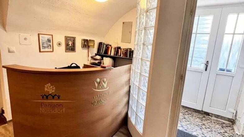 Empfangsbereich einer Pension mit Holztheke, Glasbausteinwand und gewölbter Decke.